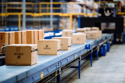 Cardboard boxes on a conveyor belt in a distribution warehouse for shipping.