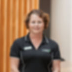 Woman wearing black shirt smiles at the camera, visible text on shirt