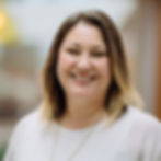 Smiling woman in white shirt, looking directly at the camera with joy.